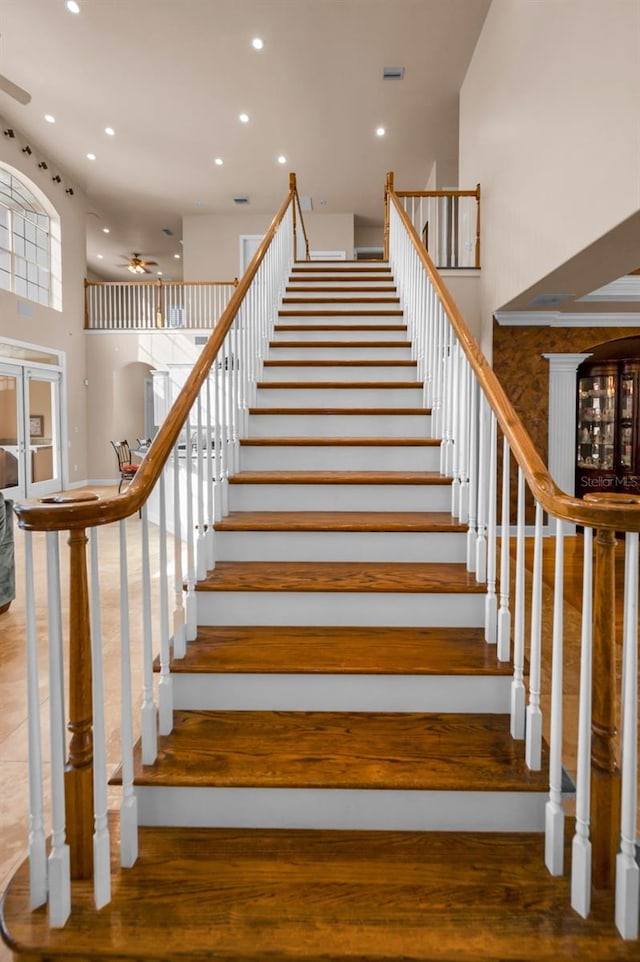 stairs with a high ceiling, a ceiling fan, and recessed lighting