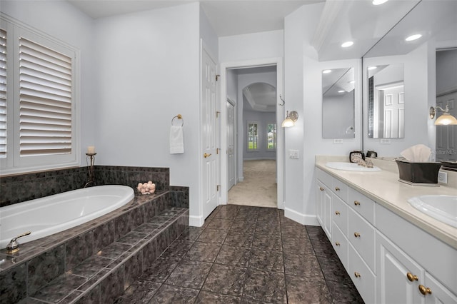 bathroom featuring a garden tub, a sink, baseboards, and double vanity