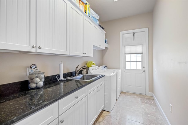 laundry room featuring separate washer and dryer, a sink, cabinet space, and baseboards