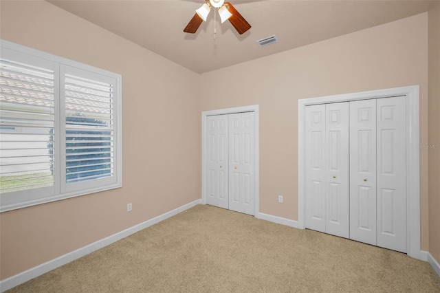 unfurnished bedroom with baseboards, carpet, visible vents, and multiple closets