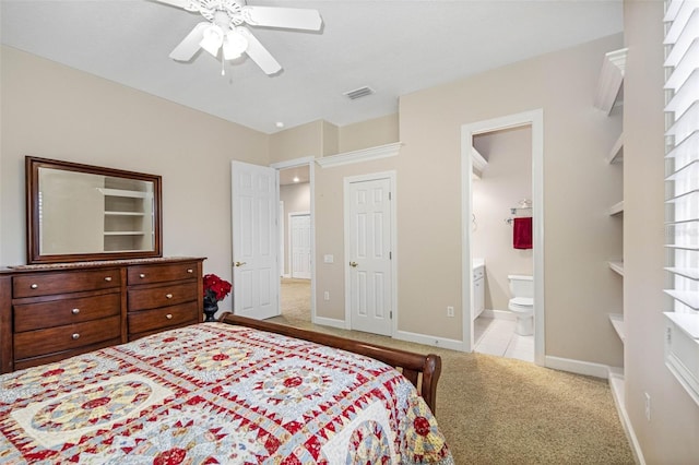 carpeted bedroom with a ceiling fan, visible vents, connected bathroom, and baseboards