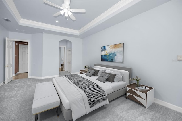 carpeted bedroom with arched walkways, crown molding, a raised ceiling, visible vents, and baseboards