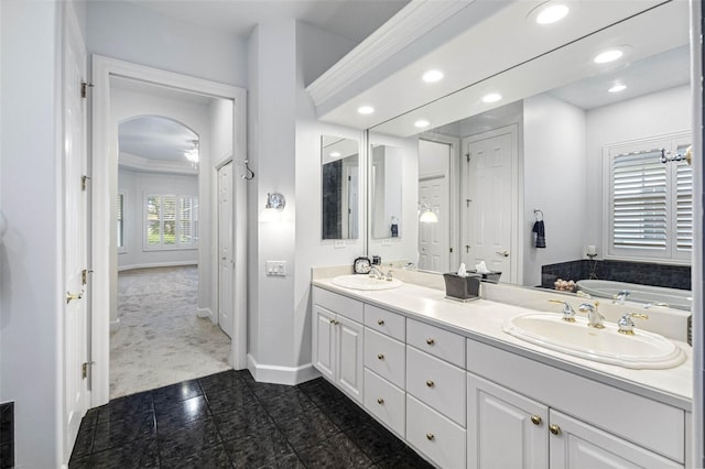 full bathroom featuring baseboards, double vanity, a sink, and recessed lighting