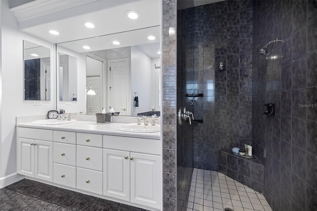 bathroom with double vanity, tiled shower, a sink, and recessed lighting