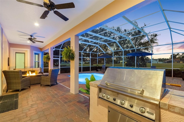 view of patio / terrace with glass enclosure, a grill, a fire pit, and exterior kitchen