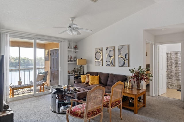 living room with a textured ceiling, carpet floors, a water view, a ceiling fan, and vaulted ceiling