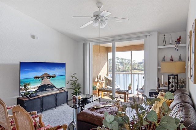 carpeted living room featuring a ceiling fan and a textured ceiling