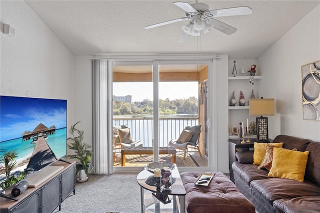 carpeted living room with a water view, a ceiling fan, visible vents, and a textured ceiling