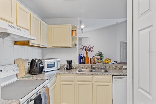 kitchen with white appliances, tasteful backsplash, light countertops, under cabinet range hood, and a sink