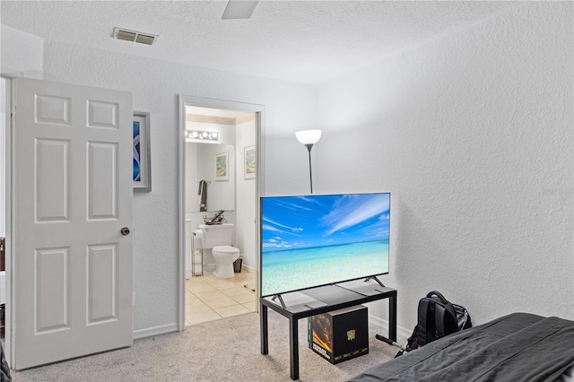 carpeted bedroom featuring visible vents, a textured wall, connected bathroom, a textured ceiling, and tile patterned floors