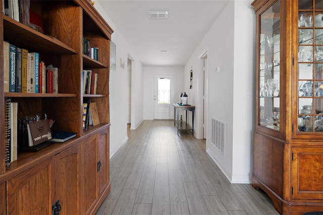 corridor featuring baseboards, visible vents, and light wood-style floors