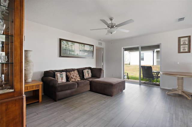 living room featuring visible vents, light wood-style flooring, and a ceiling fan