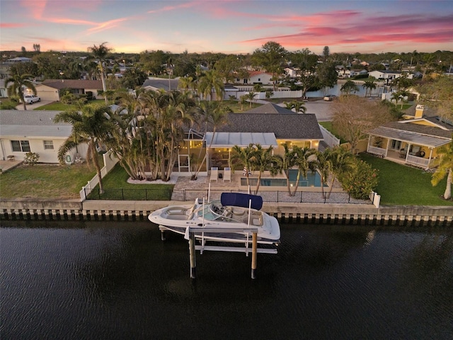 aerial view at dusk featuring a residential view and a water view