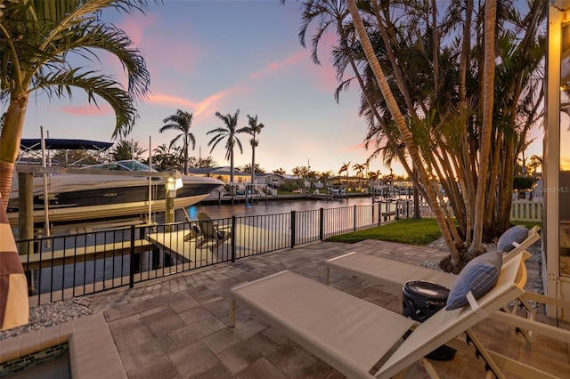 view of patio / terrace featuring a water view, boat lift, a dock, and fence