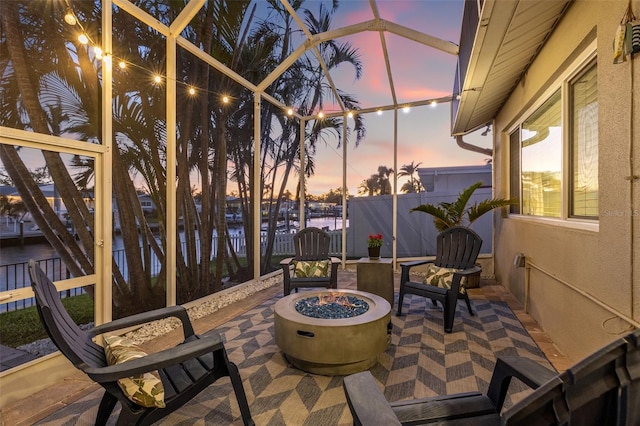 view of patio / terrace with glass enclosure, a fire pit, and fence