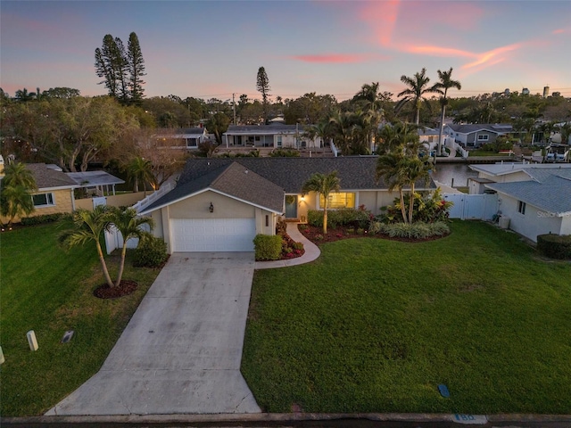 ranch-style house featuring concrete driveway, an attached garage, fence, and a yard