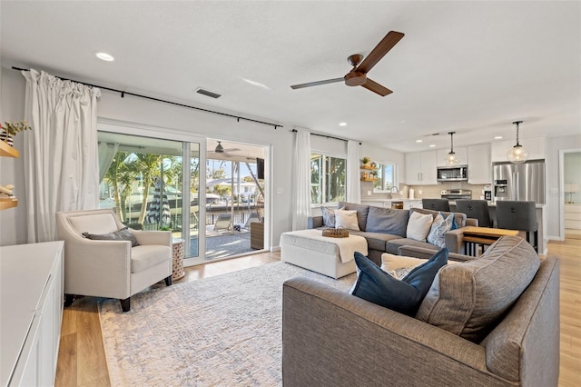 living room featuring light wood-style flooring, recessed lighting, a ceiling fan, and visible vents