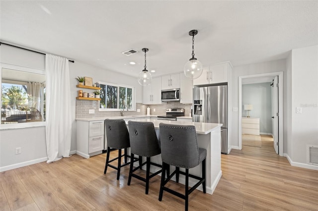 kitchen featuring visible vents, a center island, light wood-style floors, appliances with stainless steel finishes, and light countertops