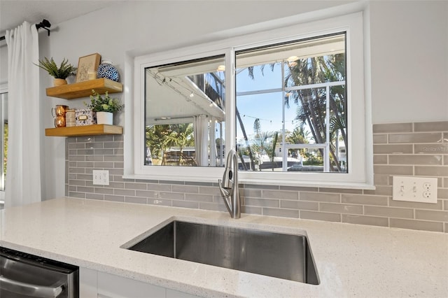 kitchen with a sink, open shelves, light stone countertops, decorative backsplash, and stainless steel dishwasher