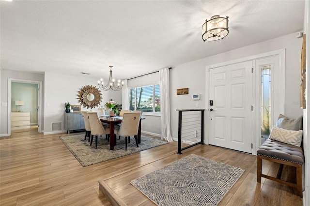 entrance foyer with visible vents, baseboards, a notable chandelier, and light wood finished floors