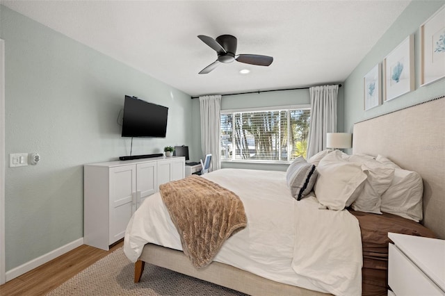 bedroom with ceiling fan, baseboards, and light wood-style floors