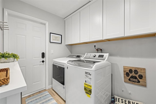 clothes washing area featuring cabinet space, washing machine and dryer, and light wood-style floors