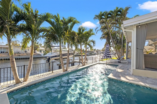 view of swimming pool featuring fence and a water view