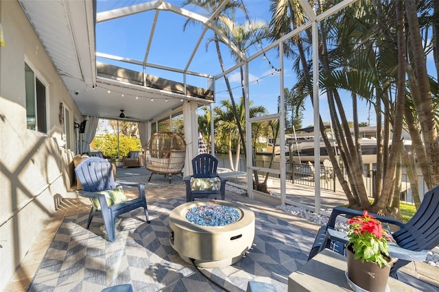 view of patio with a lanai, a ceiling fan, and an outdoor fire pit