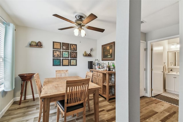 dining room with light wood finished floors, visible vents, baseboards, and a ceiling fan