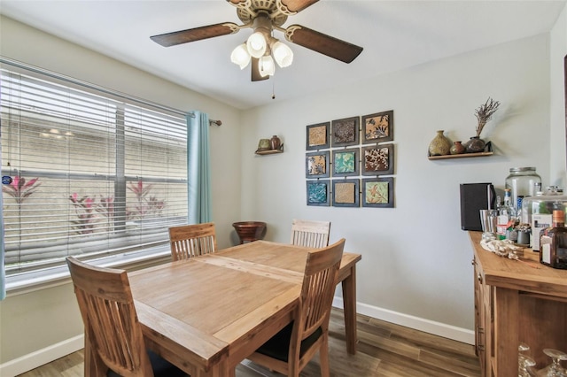 dining space with ceiling fan, baseboards, and dark wood-style flooring