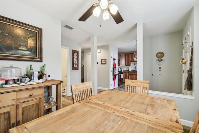 dining room featuring visible vents, ceiling fan, light wood finished floors, and baseboards