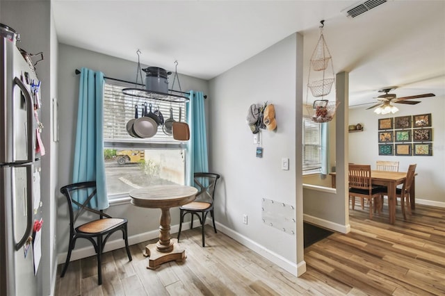 dining space featuring a ceiling fan, visible vents, baseboards, and wood finished floors