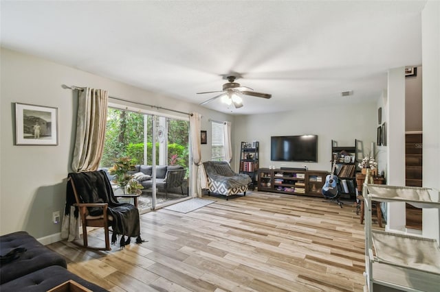 living area featuring light wood-style flooring, visible vents, ceiling fan, and baseboards