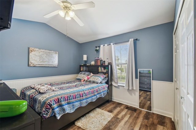 bedroom featuring a ceiling fan, lofted ceiling, wainscoting, and dark wood finished floors