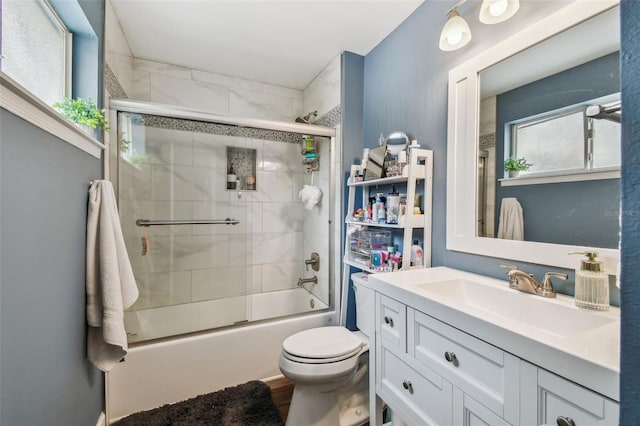 bathroom with shower / bath combination with glass door, vanity, and toilet