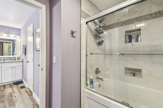 bathroom with visible vents, combined bath / shower with glass door, wood finished floors, and vanity