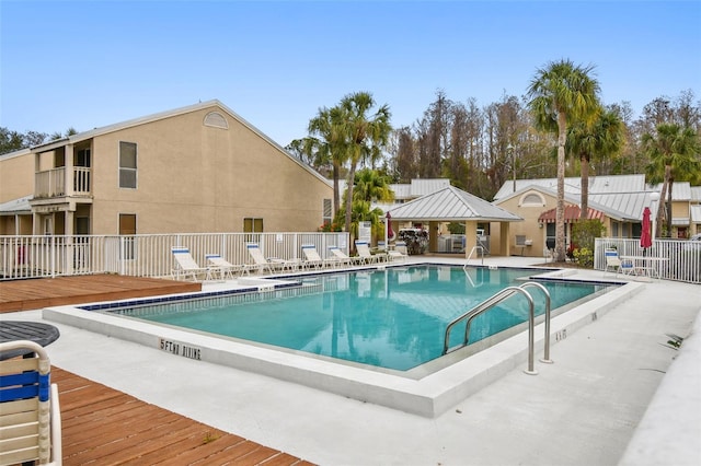 community pool with a patio area, fence, and a gazebo