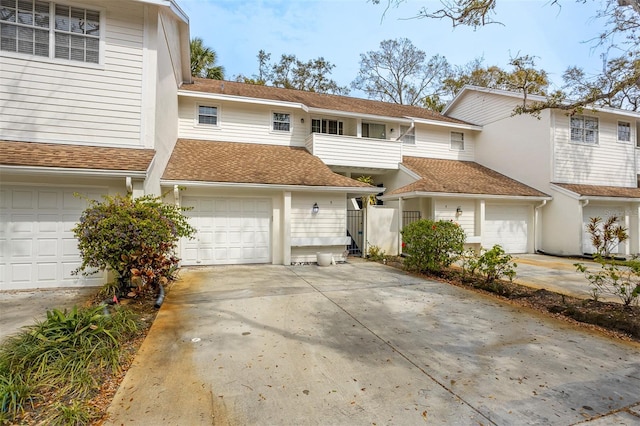 multi unit property featuring a shingled roof, concrete driveway, and a garage