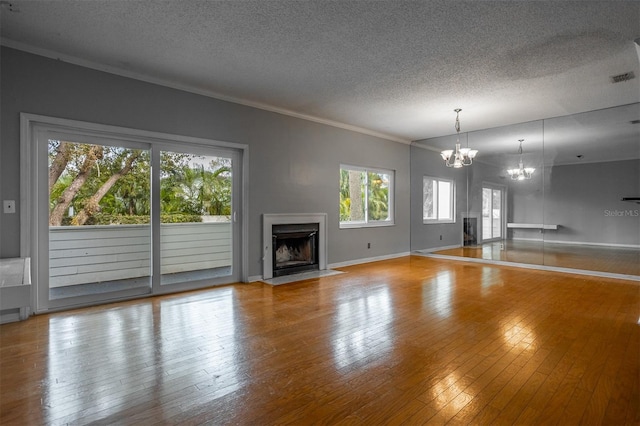 unfurnished living room with visible vents, a fireplace with flush hearth, wood finished floors, a textured ceiling, and a chandelier