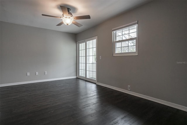 spare room featuring baseboards, dark wood finished floors, and a ceiling fan