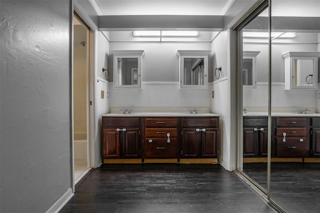 full bathroom with double vanity, a sink, walk in shower, and wood finished floors