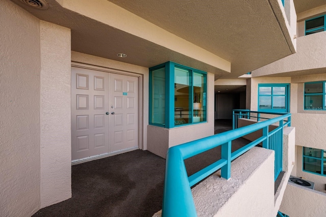 entrance to property featuring a balcony and stucco siding