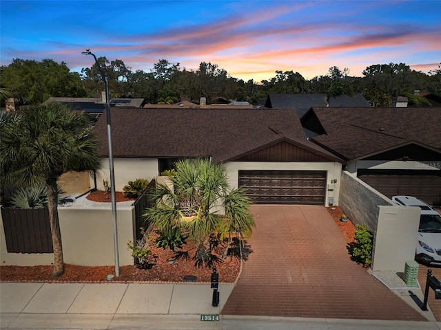 view of front of home featuring an attached garage, fence, and decorative driveway