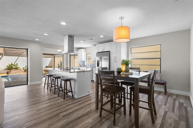 dining room featuring a textured ceiling, baseboards, dark wood-type flooring, and recessed lighting