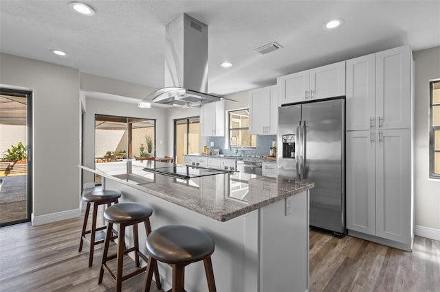 kitchen featuring a healthy amount of sunlight, island range hood, visible vents, and appliances with stainless steel finishes