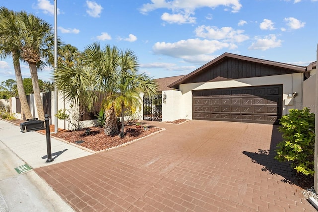 single story home featuring a garage, a gate, decorative driveway, and stucco siding