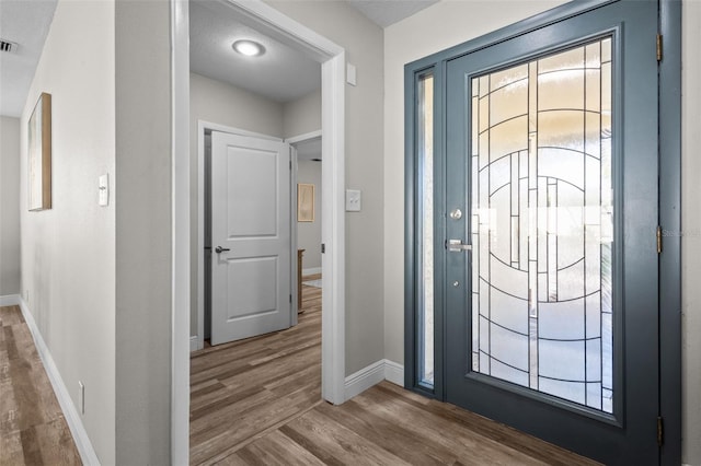 foyer featuring visible vents, baseboards, and wood finished floors