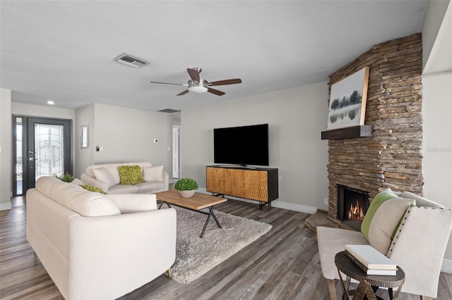 living area with baseboards, visible vents, a ceiling fan, wood finished floors, and a fireplace