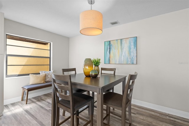 dining space featuring visible vents, baseboards, and wood finished floors