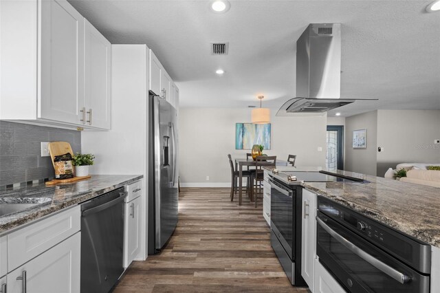 kitchen featuring dark wood-style flooring, stainless steel appliances, white cabinets, dark stone countertops, and ventilation hood